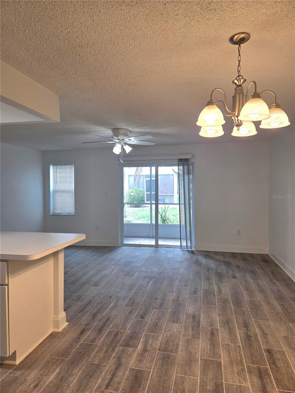 A dining area with wood-look tile flooring, a chandelier, a ceiling fan, and sliding glass doors — 353 S MCMULLEN BOOTH ROAD UNIT 133, CLEARWATER, FL