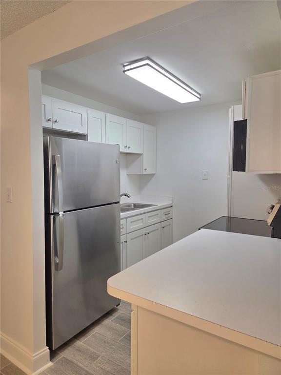 A kitchen features white cabinets, stainless steel appliances, and a white countertop — 353 S MCMULLEN BOOTH ROAD UNIT 133, CLEARWATER, FL
