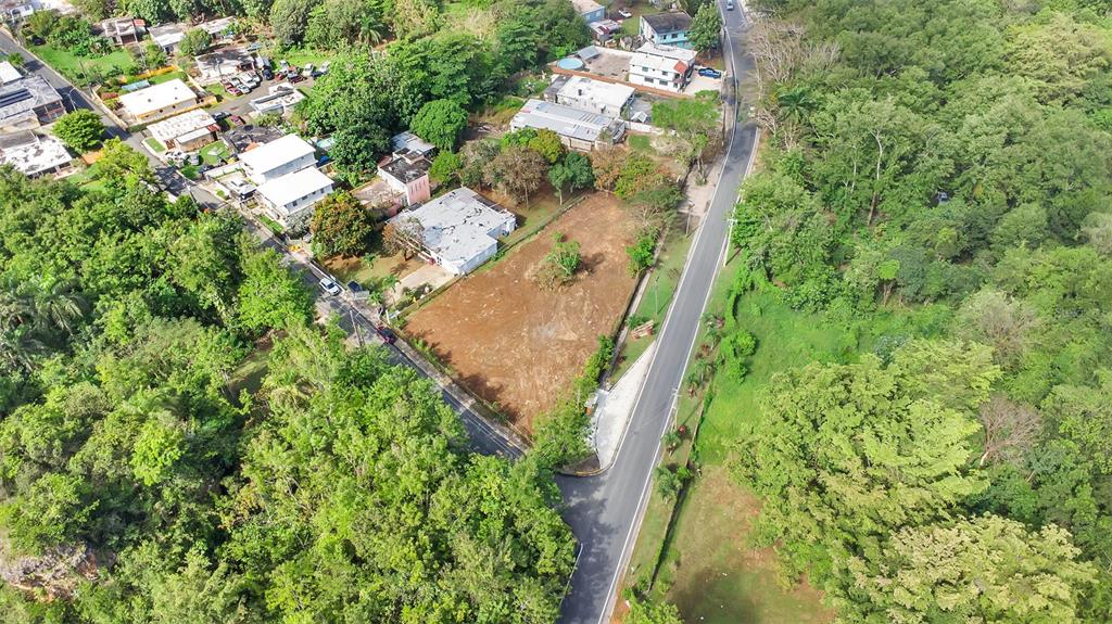 An aerial view shows a vacant, cleared rectangular lot situated between a road and houses — Km 3.6 695, DORADO, PR