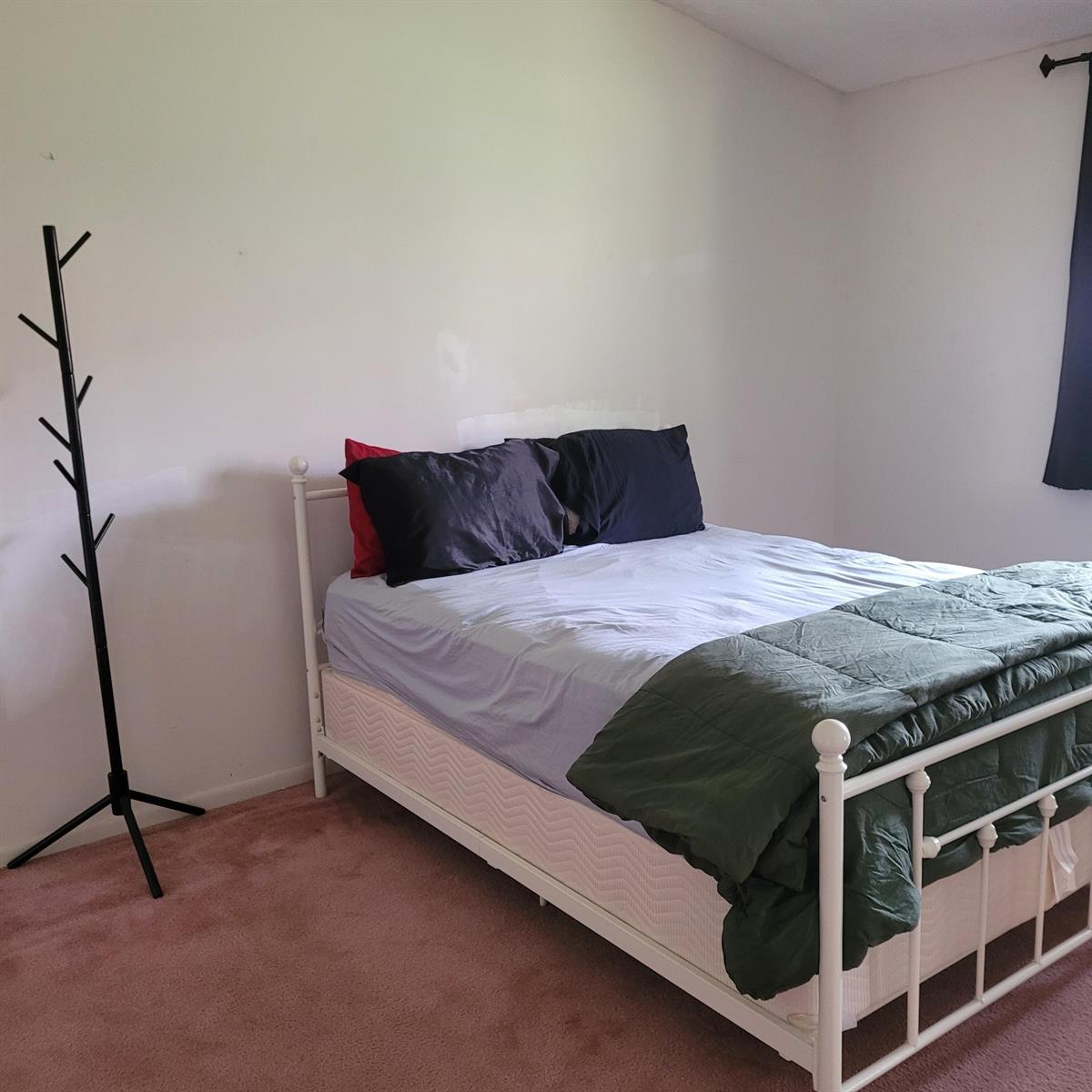 A bedroom features a white metal bed frame, pink carpeting, and a black coat rack — 135 Meander Circle, Royal Palm Beach FL 33411, ROYAL PALM BEACH, FL
