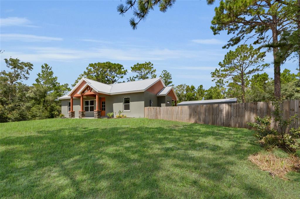 A single-story house with a metal roof and wooden porch columns sits on a grassy lot — 1170 CR 543B, SUMTERVILLE, FL
