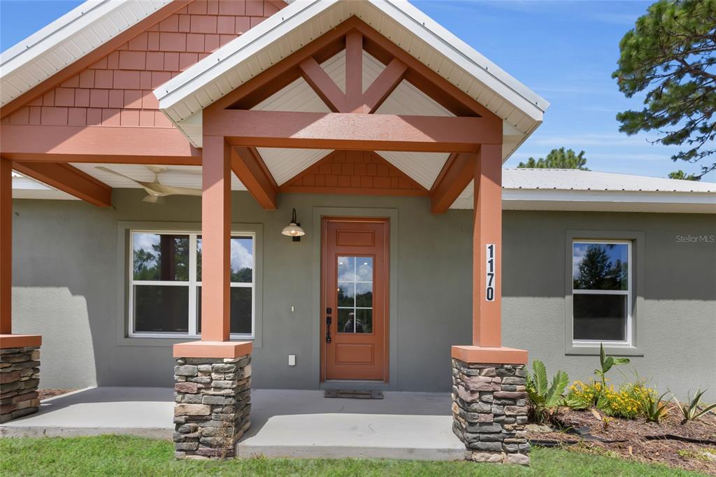 The front exterior of a house features a covered porch with stone-based columns and shingles — 1170 CR 543B, SUMTERVILLE, FL