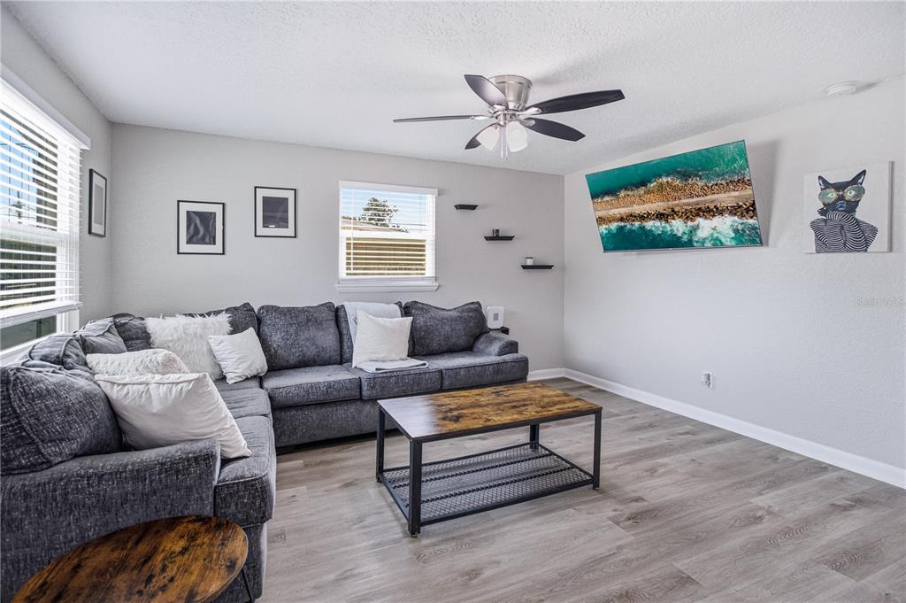 A living room features a grey sectional sofa, a coffee table, and a wall-mounted television — 465 SIGSBEE COURT, ORANGE PARK, FL