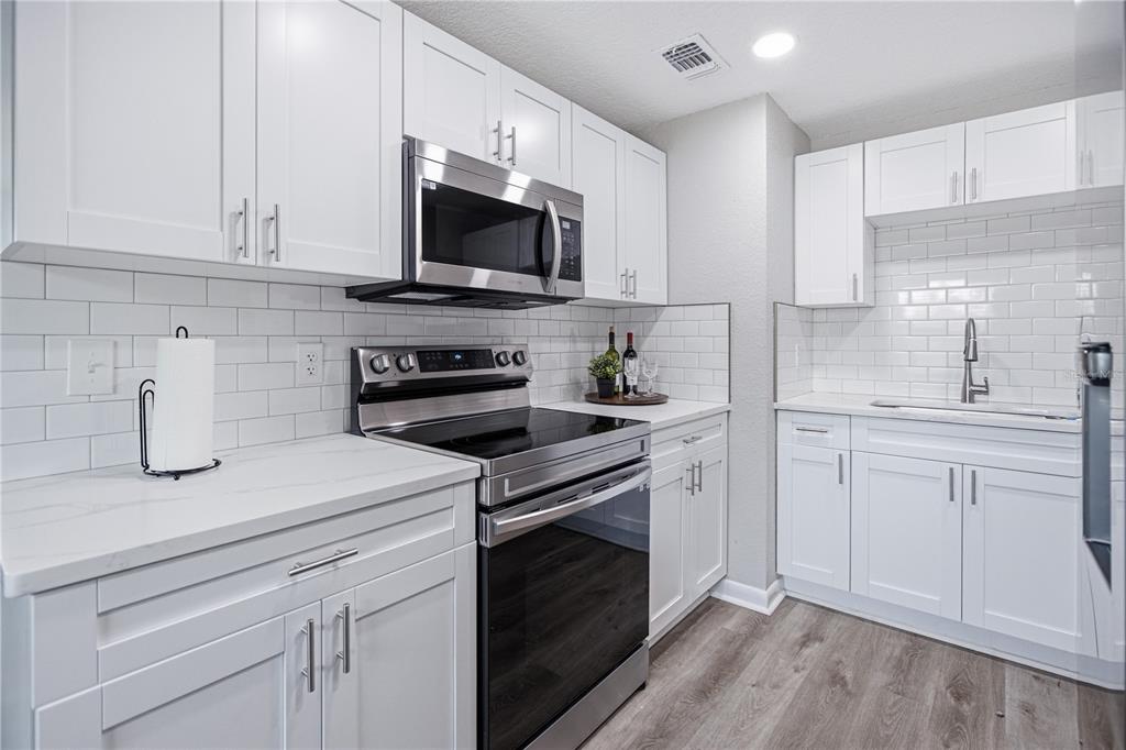 A modern kitchen features white cabinets, stainless steel appliances, white countertops, and a subway tile backsplash — 465 SIGSBEE COURT, ORANGE PARK, FL