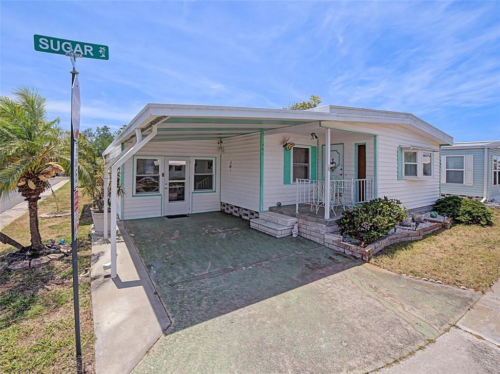 A single-story mobile home with a carport, white siding, and a small front porch — 701 SUGAR PALM STREET, LARGO, FL