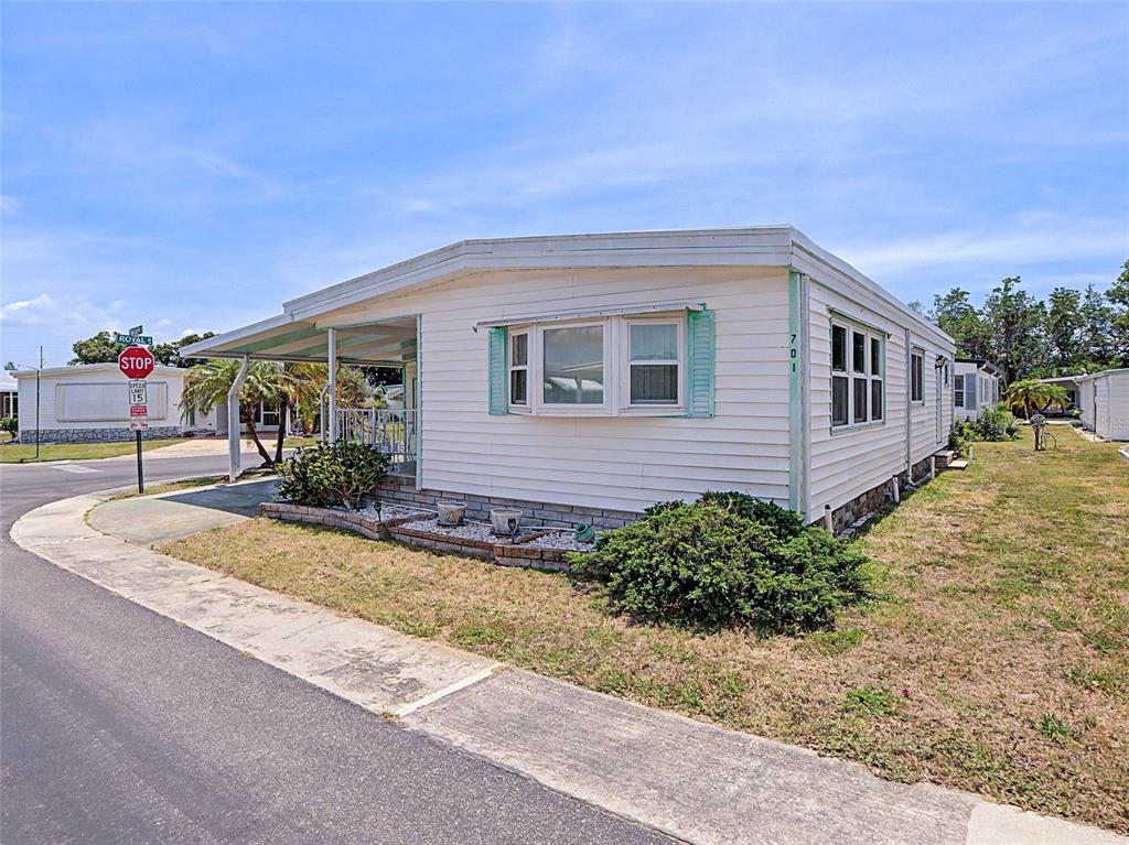 A single-story mobile home with white siding, a covered porch, and a bay window — 701 SUGAR PALM STREET, LARGO, FL