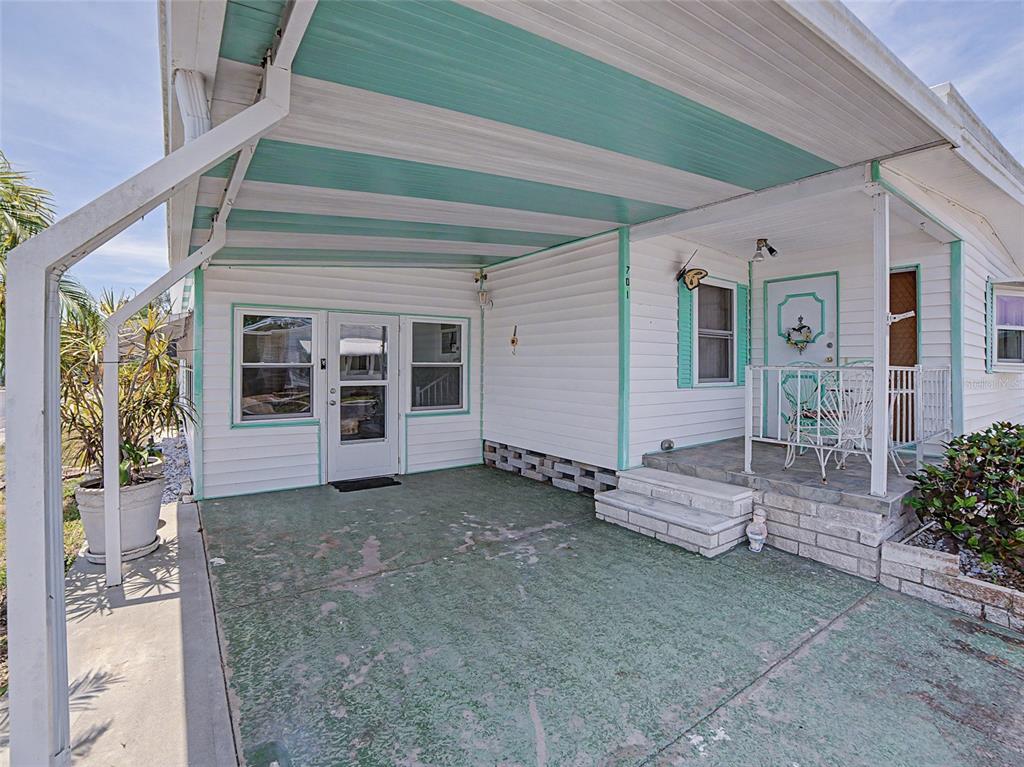 A white mobile home exterior features a covered carport, a small front porch, and teal trim — 701 SUGAR PALM STREET, LARGO, FL