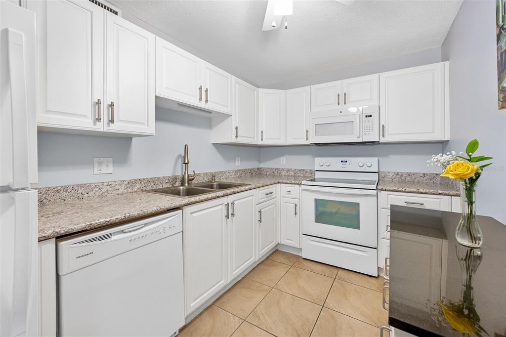 A kitchen features white cabinets, granite countertops, a white dishwasher, and a white range — 2711 N HALIFAX AVENUE UNIT 478, DAYTONA BEACH, FL