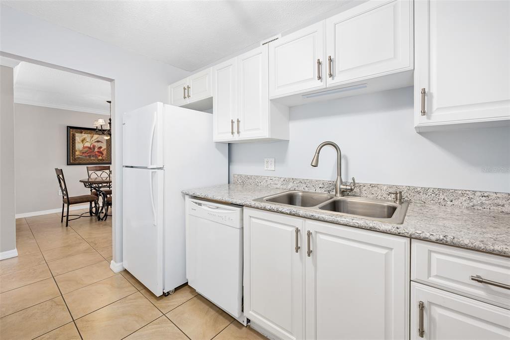 A kitchen with white cabinets, granite countertops, a stainless steel sink, and a white refrigerator — 2711 N HALIFAX AVENUE UNIT 478, DAYTONA BEACH, FL
