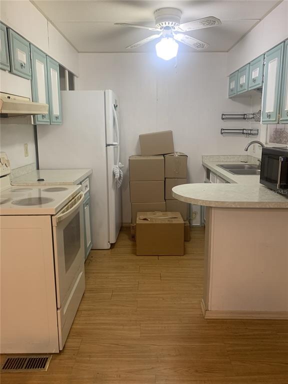 A kitchen features white appliances, light-colored cabinets, a ceiling fan, and wood-look flooring — 14391 SANDHURST STREET, BROOKSVILLE, FL