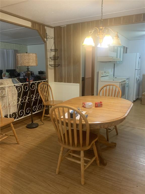 A dining area features a wooden table and chairs, wood-paneled walls, and a hanging light fixture — 14391 SANDHURST STREET, BROOKSVILLE, FL