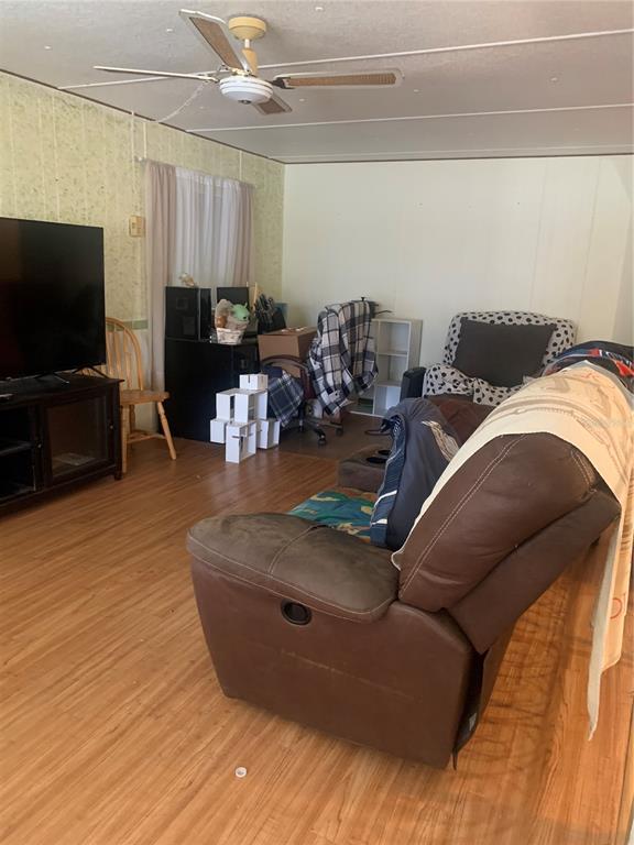 A living room features wood-look flooring, a brown recliner, a television, and a ceiling fan — 14391 SANDHURST STREET, BROOKSVILLE, FL