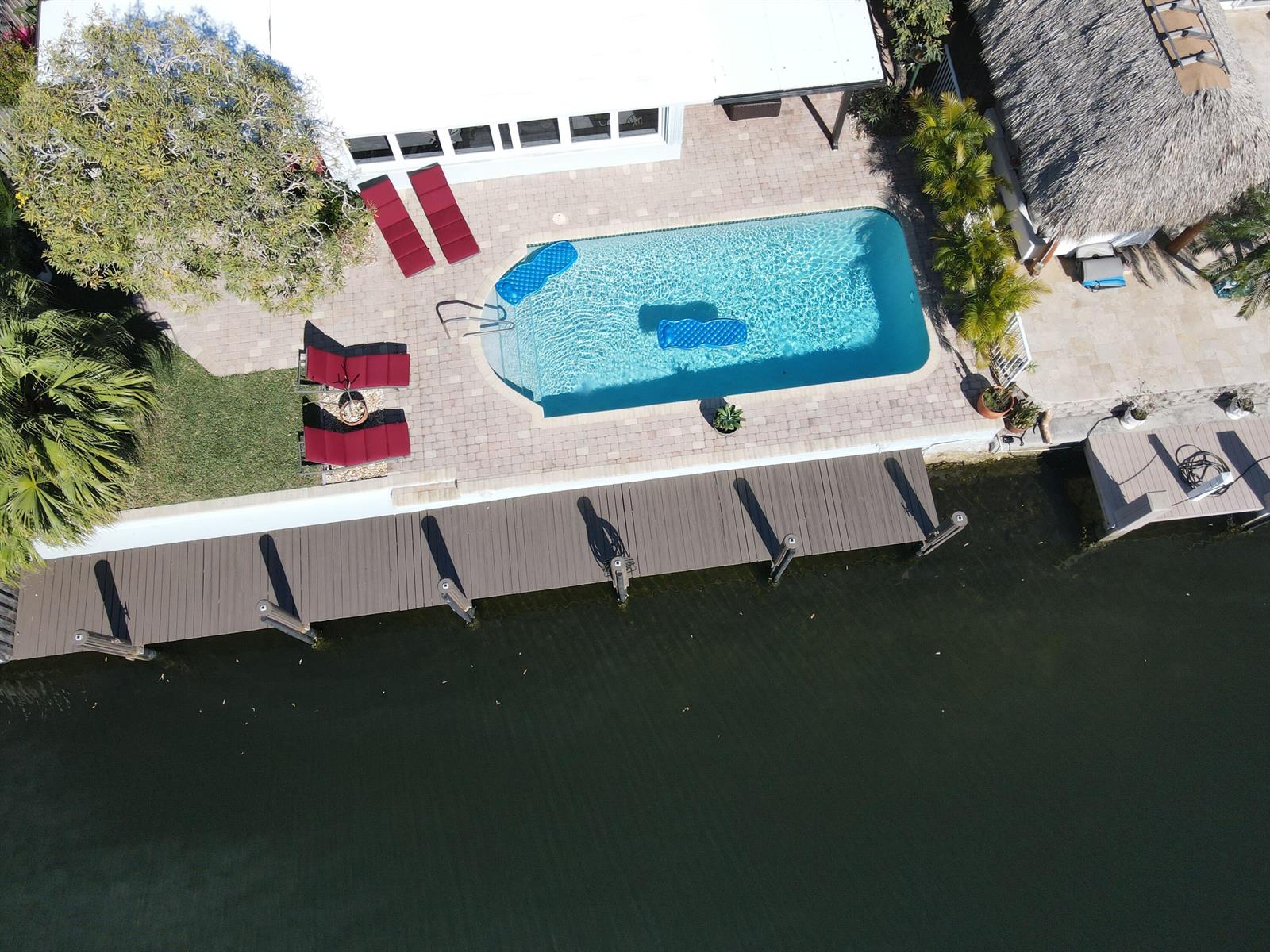 An aerial view shows a swimming pool, lounge chairs, a wooden dock, and a canal — 2548 SE 14th Street E, Pompano Beach FL 33062, POMPANO BEACH, FL