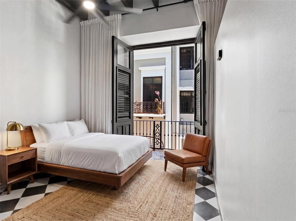 A bedroom features a platform bed, a leather chair, and doors opening to a balcony — 252 CALLE FORTALEZA UNIT 252, SAN JUAN, PR