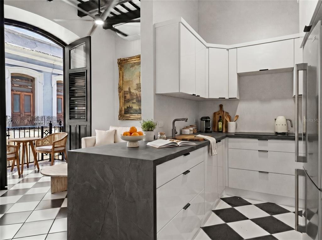 A modern kitchen with white cabinets and dark countertops opens onto a balcony with checkered floors — 252 CALLE FORTALEZA UNIT 252, SAN JUAN, PR