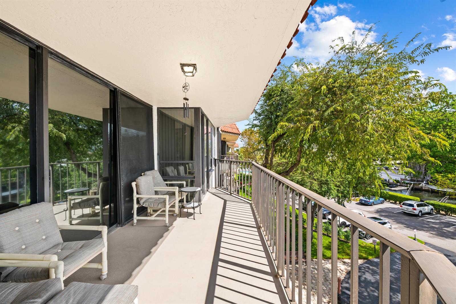 A balcony with outdoor seating overlooks a parking lot and trees under a blue sky — 799 Jeffery Street # 4050, Boca Raton FL 33487, BOCA RATON, FL