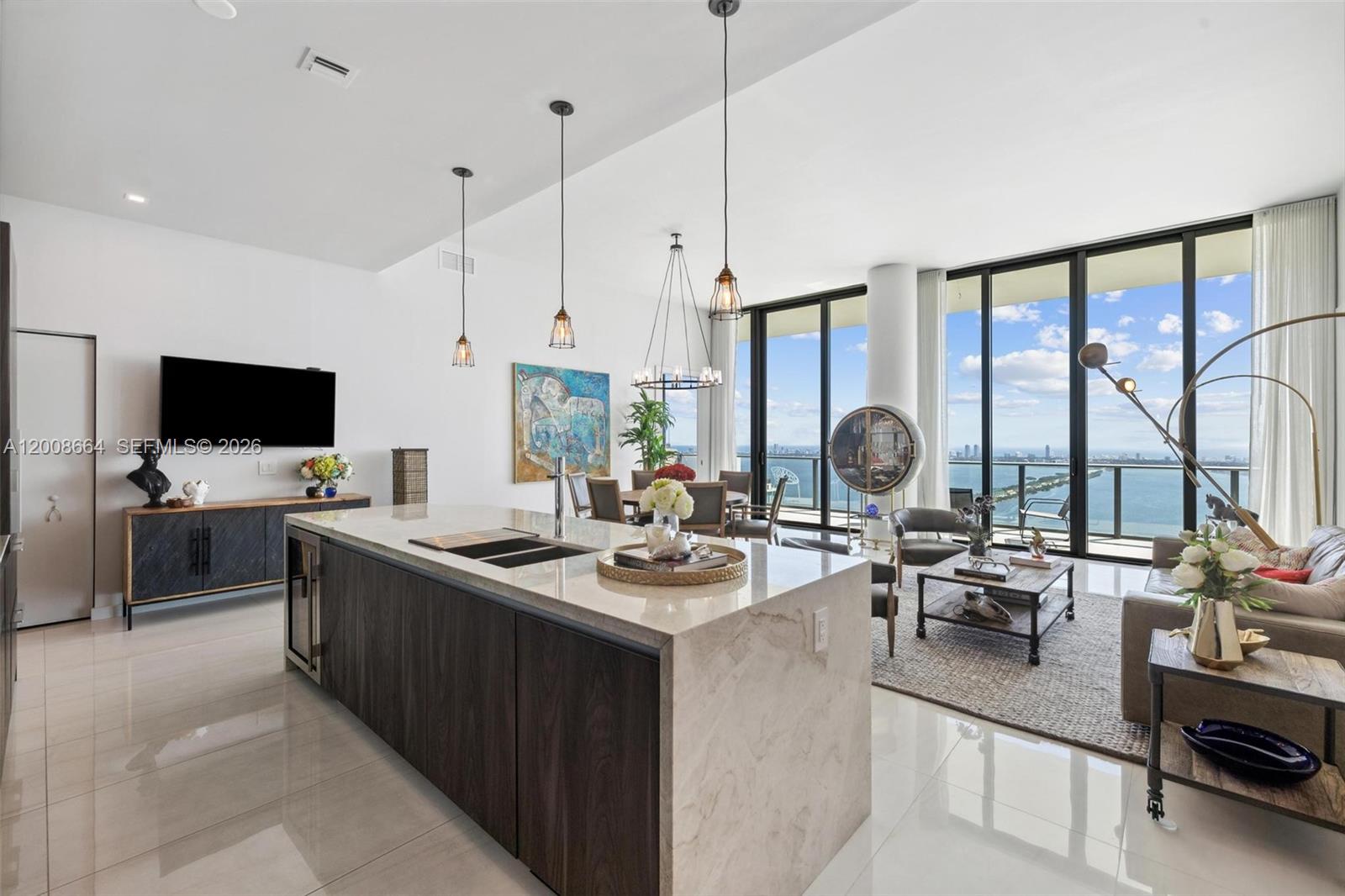 A modern open-concept kitchen and living area features a large stone island and floor-to-ceiling windows — 480 NE 31st St, Miami FL 33137, MIAMI, FL