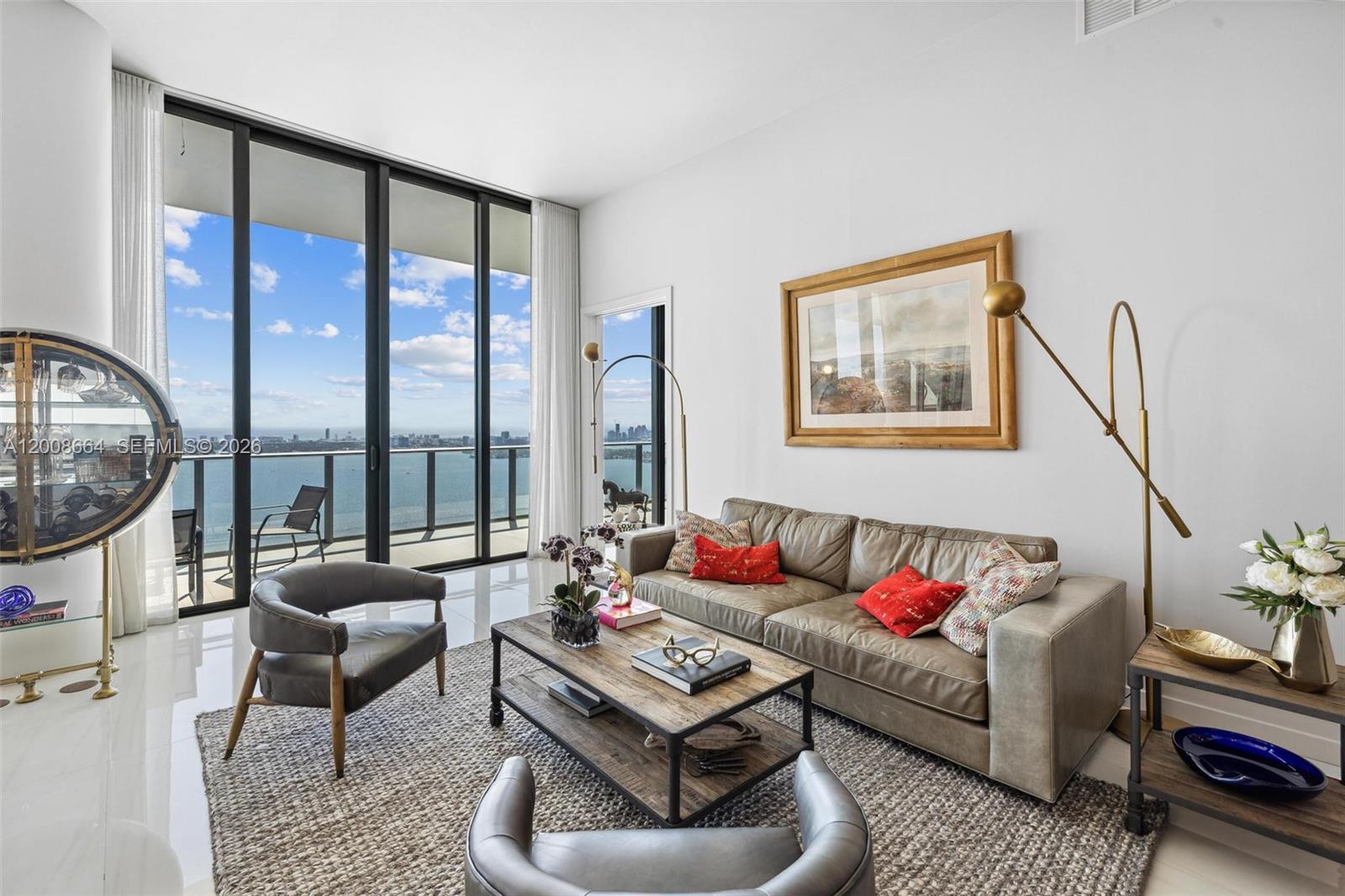 A modern living room features a leather sofa, two armchairs, and floor-to-ceiling windows overlooking water — 480 NE 31st St, Miami FL 33137, MIAMI, FL