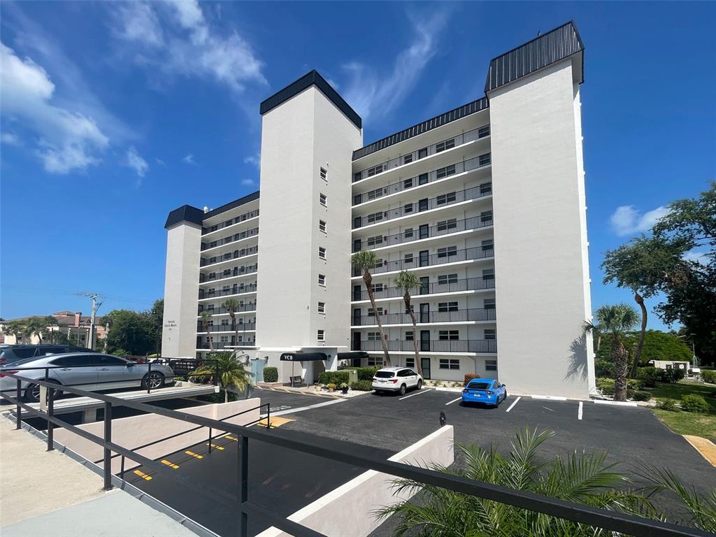 A multi-story apartment building features white exterior walls, black trim, and a paved parking lot — 232 SAINT AUGUSTINE AVENUE UNIT 207, VENICE, FL