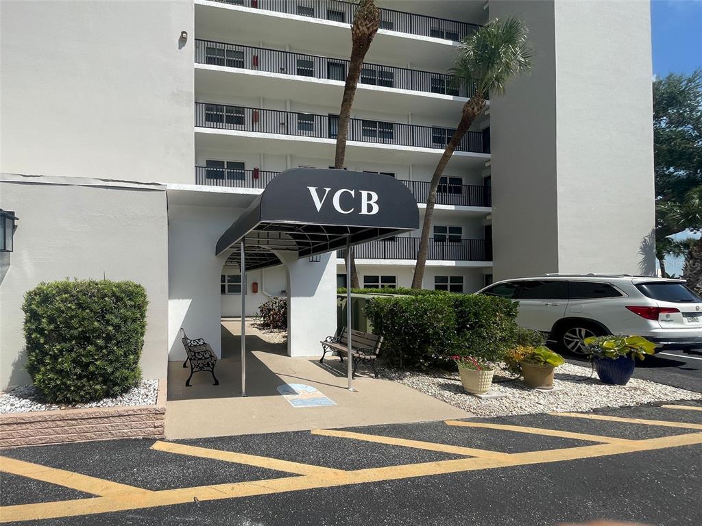 The exterior of a multi-story apartment building features a black awning labeled VCB — 232 SAINT AUGUSTINE AVENUE UNIT 207, VENICE, FL