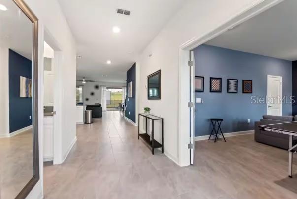 A hallway with light tile flooring leads to an open living area with blue accent walls — 9254 SOMMERSET HILLS DRIVE, DAVENPORT, FL