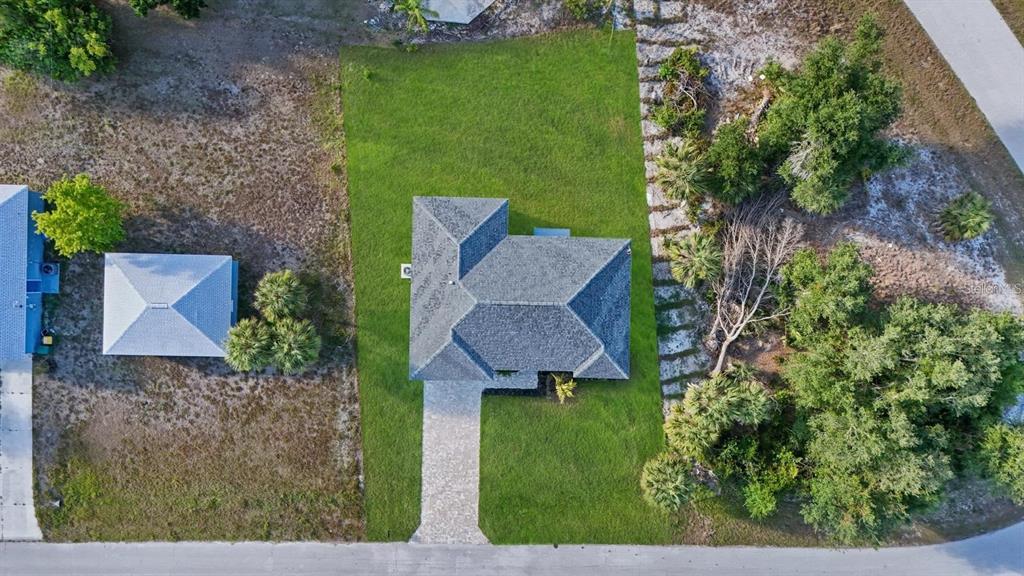 An aerial view shows a house with a gray roof, a paved driveway, and surrounding landscaping — 3471 WINONA STREET, PORT CHARLOTTE, FL