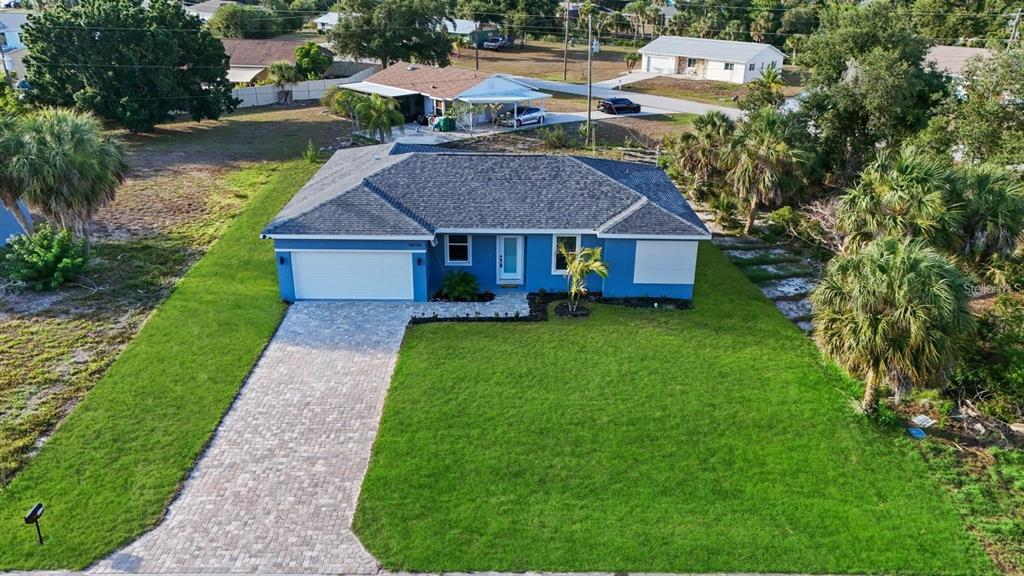 An aerial view shows a blue single-story house with a paved driveway and green lawn — 3471 WINONA STREET, PORT CHARLOTTE, FL