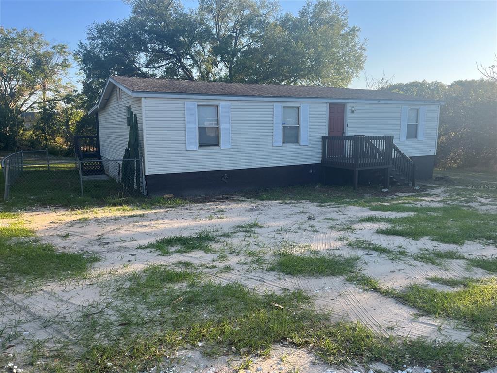 A single-story mobile home with light siding, a dark skirt, and a wooden front deck — 142 WINSTON AVENUE, LAKE WALES, FL