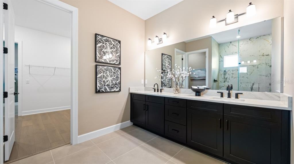 A bathroom features a double vanity with black cabinets, a large mirror, and tiled floors — 7391 MOONBEAM AVENUE, SARASOTA, FL
