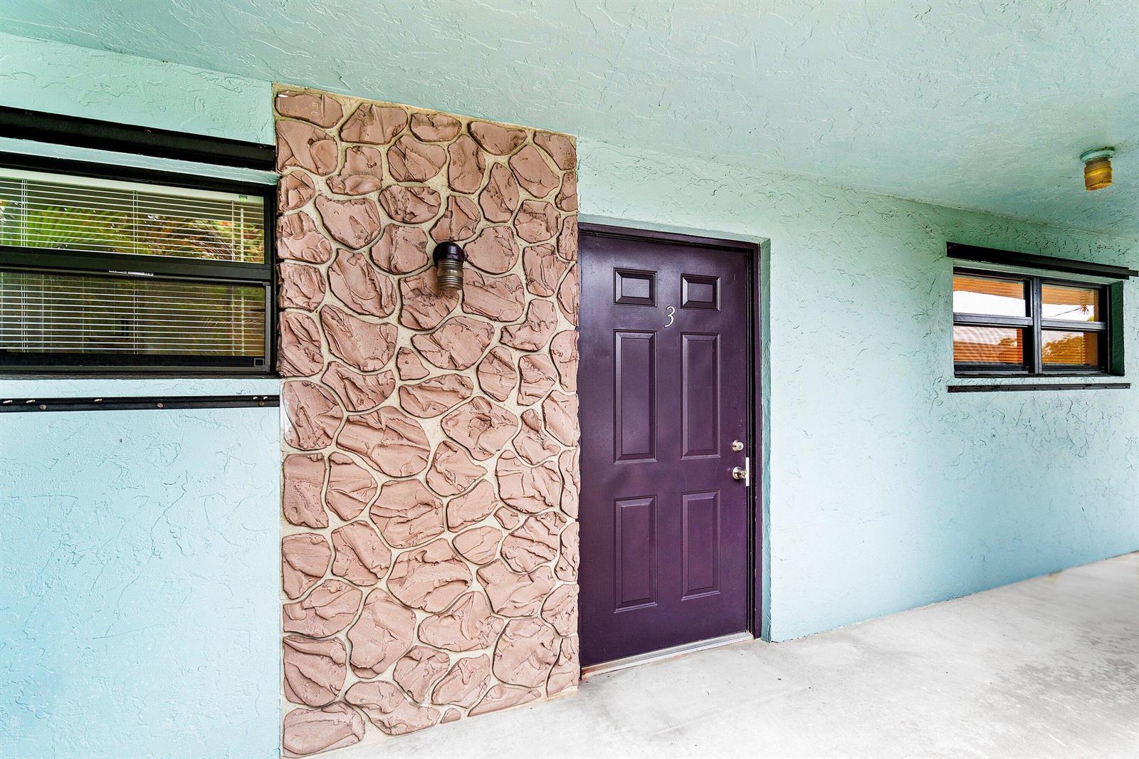 A purple front door with the number three sits beside a decorative stone accent wall — 626 N Federal Highway Unit 3, FL 33460, FL