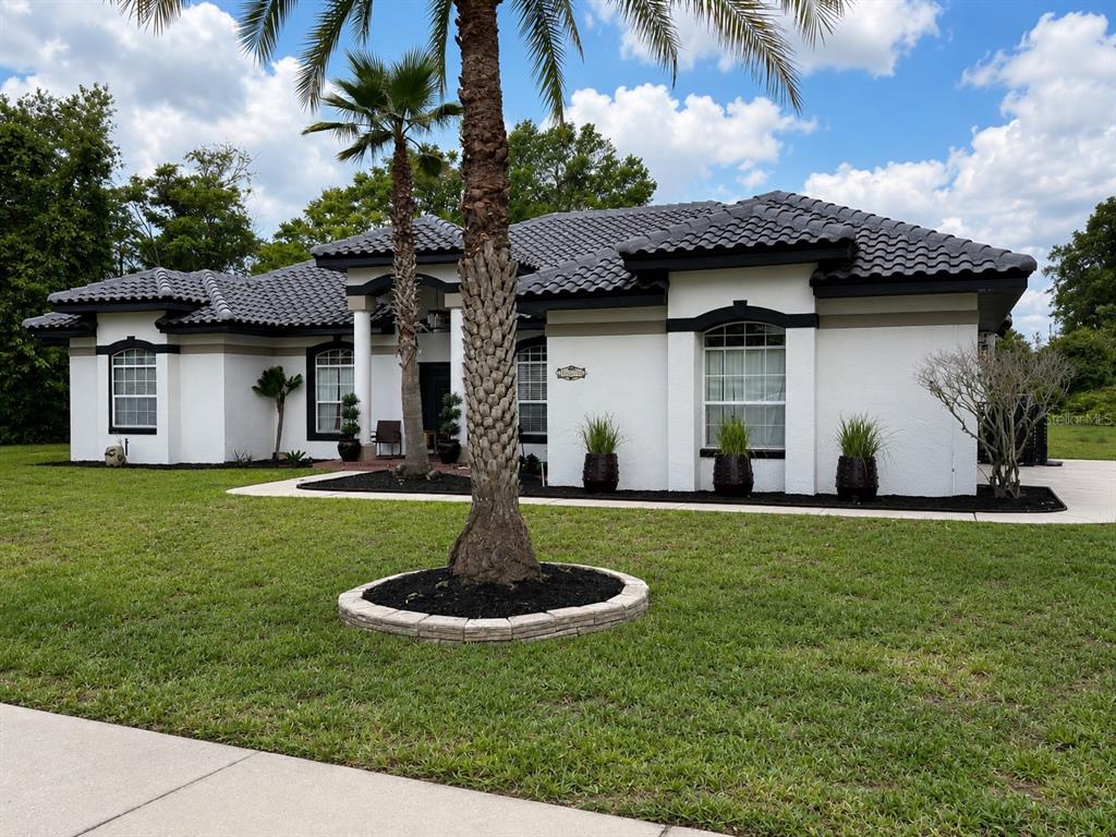 A single-story white house with a dark tiled roof and a palm tree in front — 1043 W SEAGATE DRIVE, DELTONA, FL