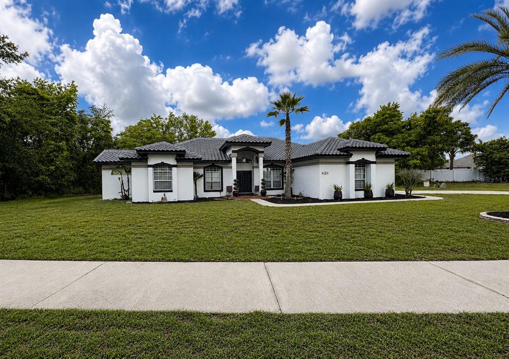 A single-story white house with a dark tiled roof and a large front lawn — 1043 W SEAGATE DRIVE, DELTONA, FL