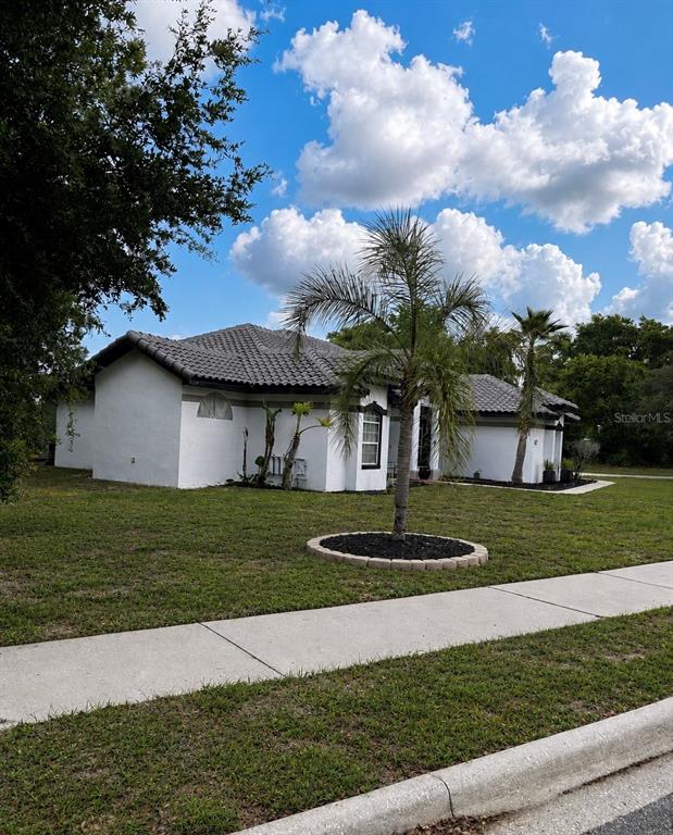 A single-story white house with a gray tile roof and palm trees in the yard — 1043 W SEAGATE DRIVE, DELTONA, FL