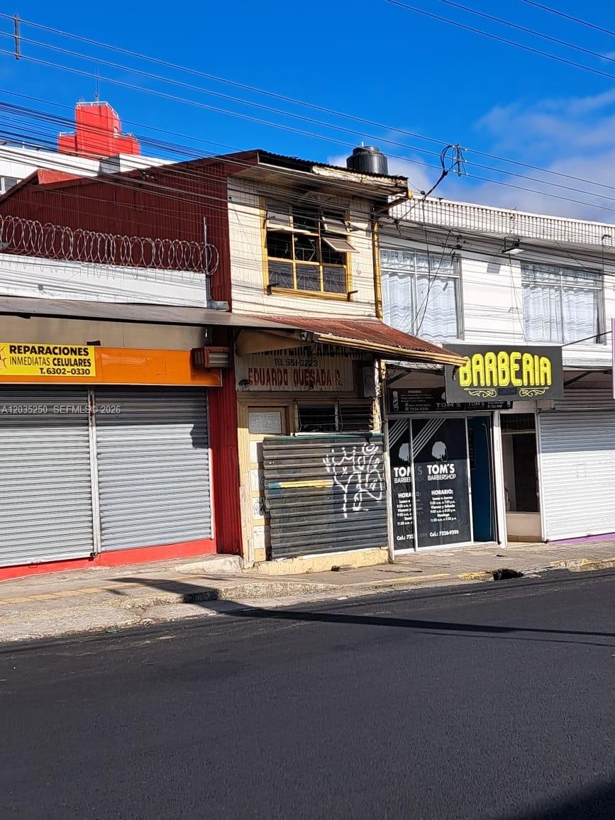 A street-level view of three adjacent commercial storefronts with metal security shutters and signage — Avenida Central Cartago, FL 000, FL