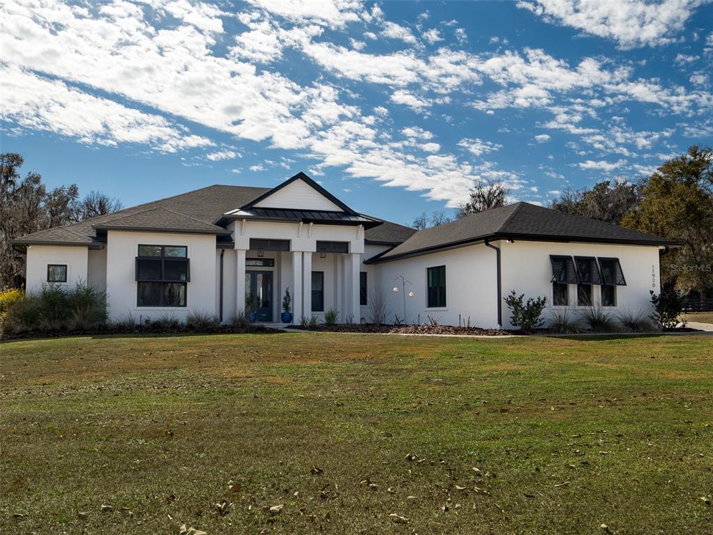 A white single-story house with a dark roof and black shutters sits on a lawn — 11920 SE 22ND AVENUE ROAD, OCALA, FL