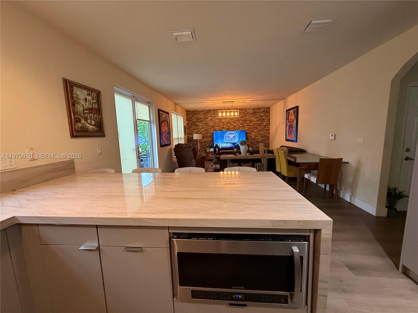 A kitchen island with a built-in microwave faces an open-concept living and dining area — 17012 SW 91st Ter, Miami FL 33196, MIAMI, FL