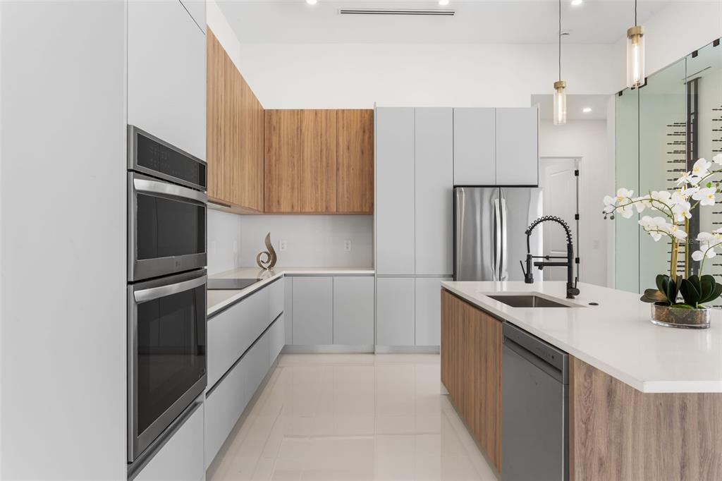 A modern kitchen features light gray cabinets, wood-tone accents, stainless steel appliances, and a white island — 10 SW 33RD AVENUE, CAPE CORAL, FL