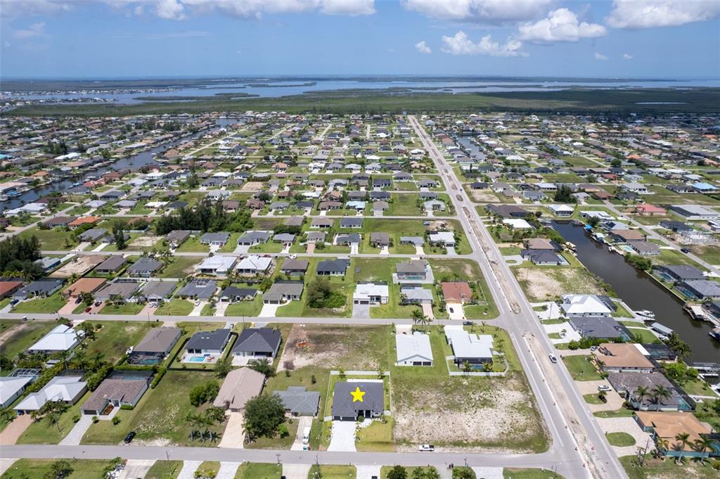 An aerial view shows a residential neighborhood with a single house marked by a star — 10 SW 33RD AVENUE, CAPE CORAL, FL