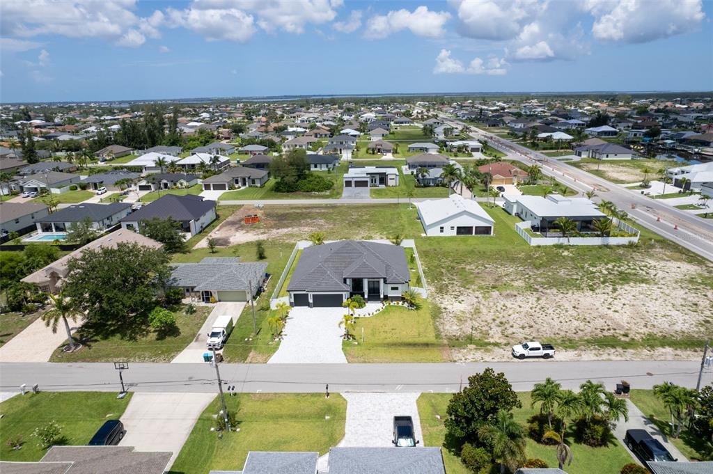 An aerial view shows a residential neighborhood with several single-family homes and vacant lots — 10 SW 33RD AVENUE, CAPE CORAL, FL