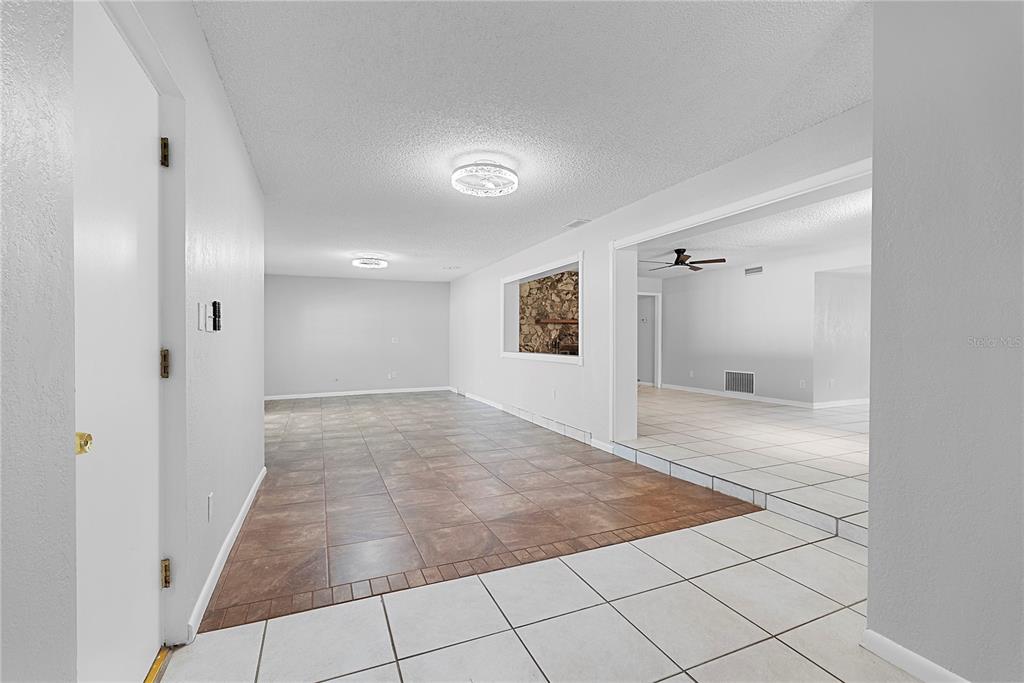 An interior view shows a room with brown tile flooring, white walls, and a stone accent — 165 DUNCAN TRAIL, LONGWOOD, FL