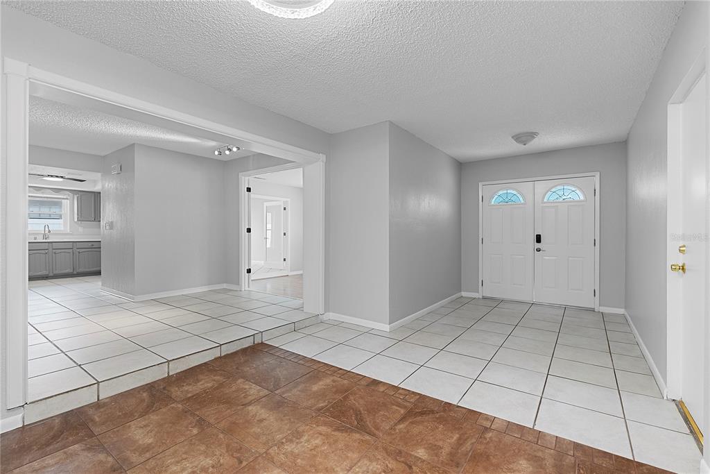 An entryway with white tile floors leads to a kitchen and a double-door front entrance — 165 DUNCAN TRAIL, LONGWOOD, FL