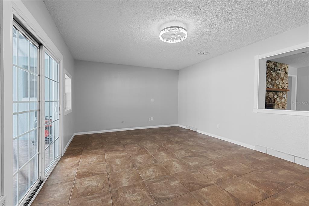 An empty room features brown tile flooring, light gray walls, and a sliding glass door — 165 DUNCAN TRAIL, LONGWOOD, FL
