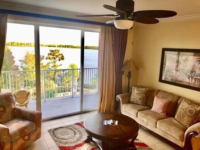 A living room features a sofa, armchair, round coffee table, ceiling fan, and a balcony view — 13415 BLUE HERON BEACH DRIVE UNIT 304, ORLANDO, FL
