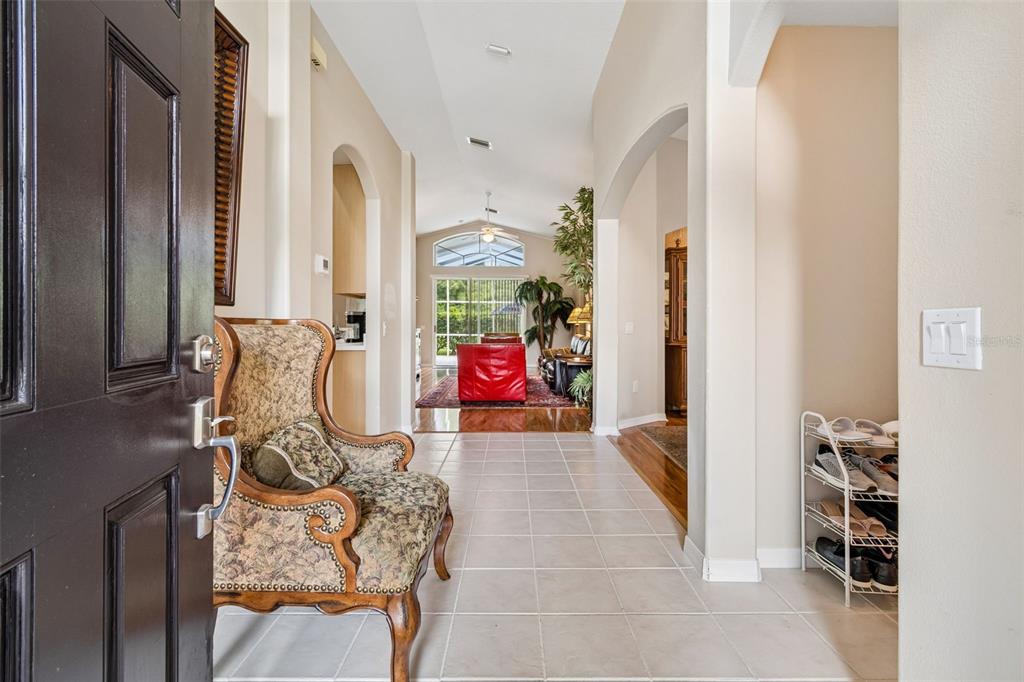 A tiled entryway leads into a living room with a red sofa and vaulted ceilings — 19308 SANDY SPRINGS CIRCLE, LUTZ, FL