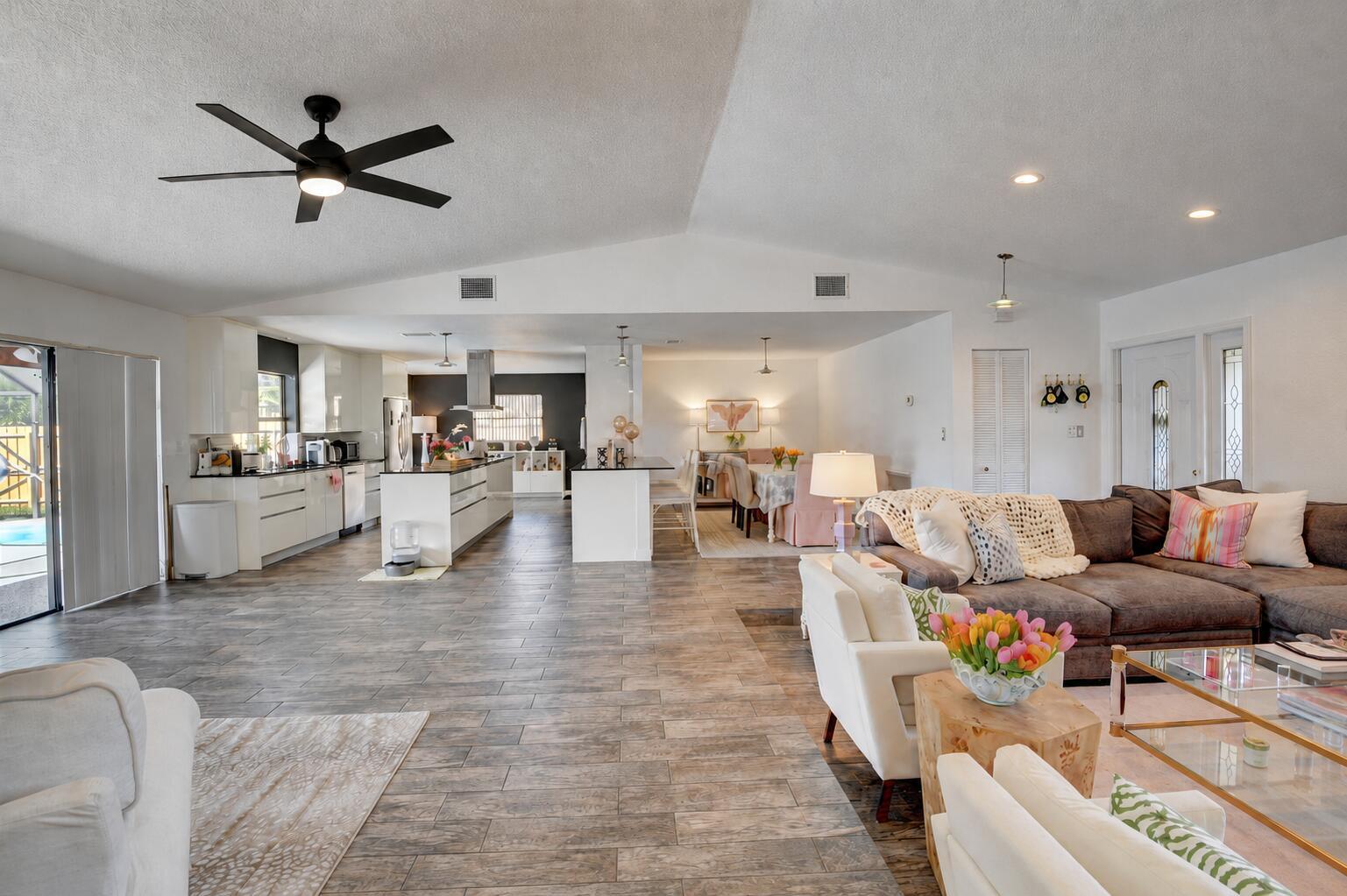 An open-concept living area features a modern kitchen, dining space, and a spacious lounge area — 17679 Woodview Terrace, Boca Raton FL 33487, BOCA RATON, FL