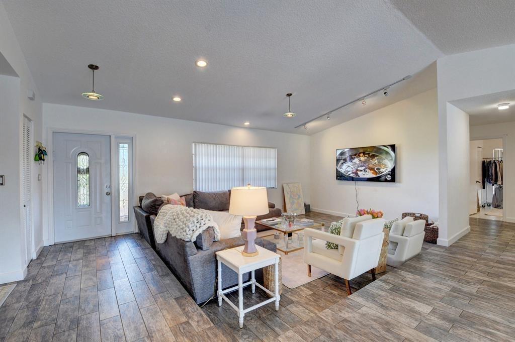 A living room features gray tile flooring, a sectional sofa, white armchairs, and a television — 17679 Woodview Terrace, Boca Raton FL 33487, BOCA RATON, FL