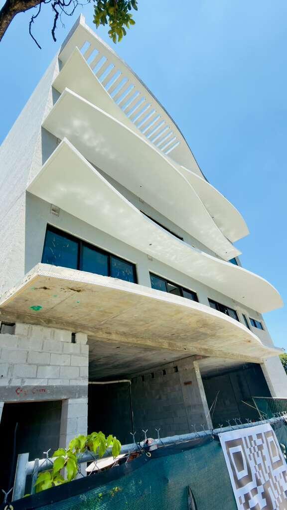 Low-angle view of a modern building under construction featuring curved concrete balconies and exterior walls — 4110 NW 22nd Avenue # 2, Miami FL 33142, MIAMI, FL