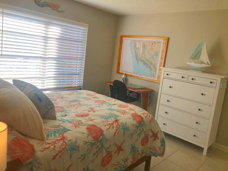 A bedroom features a bed with a seashell-patterned quilt, a desk, and a white dresser — 1358 ROCK DOVE COURT UNIT 7, PUNTA GORDA, FL