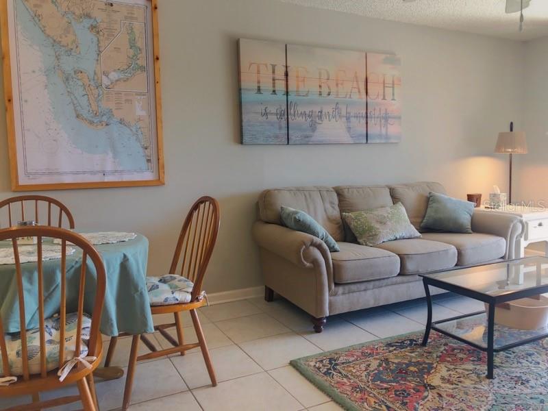 A living room features a beige sofa, a dining table with wooden chairs, and wall art — 1358 ROCK DOVE COURT UNIT 7, PUNTA GORDA, FL