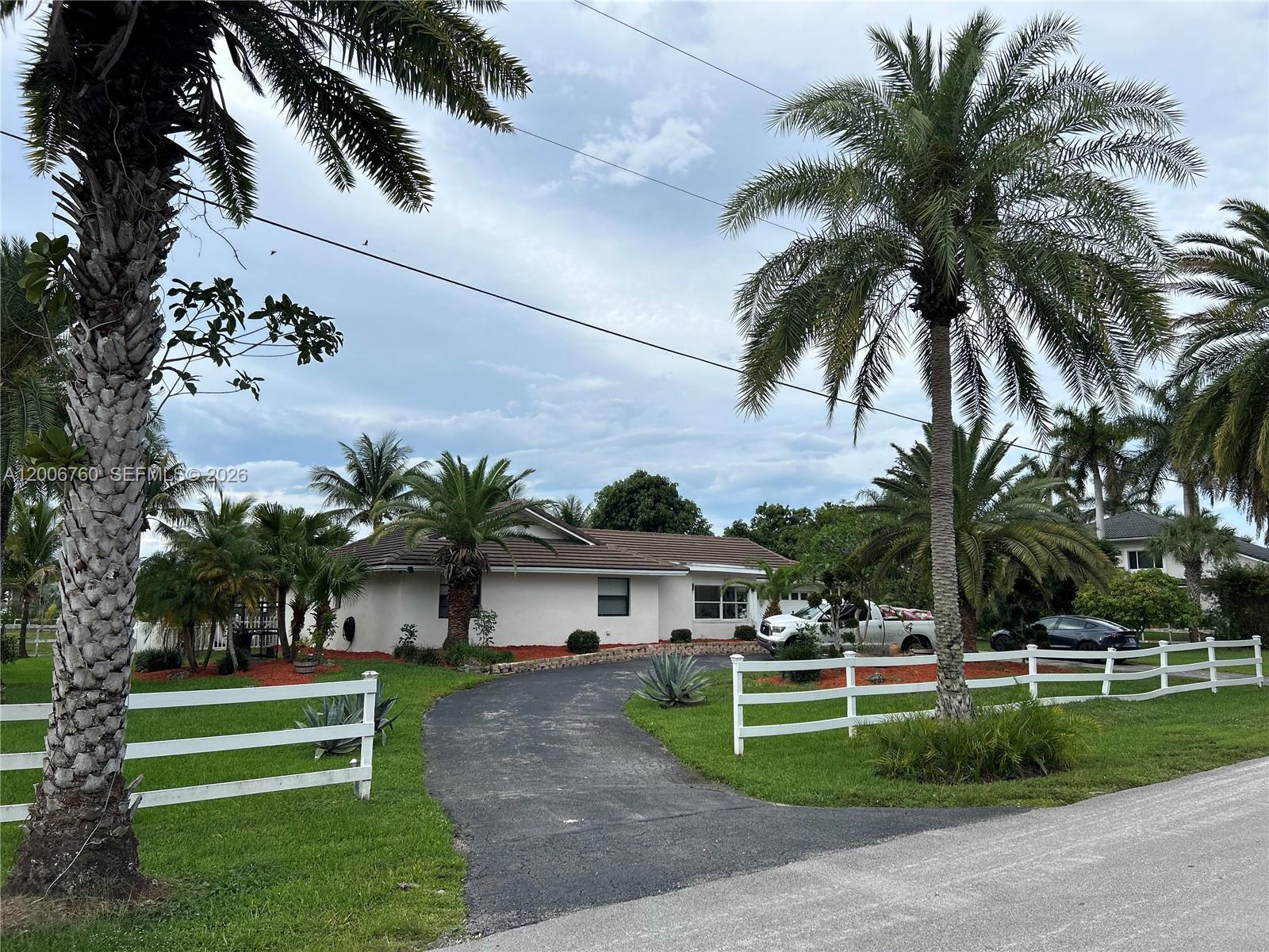 A single-story house with a white exterior, a curved driveway, and palm trees — 11781 NW 14th St, Plantation FL 33323, PLANTATION, FL
